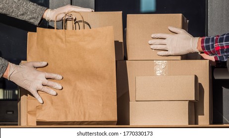 Couriers In Protective Gloves Put Parcels On The Doorstep Of The House