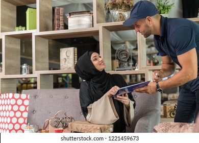 Courrier giving the goods to the girl wearing hijab in the coffe shop.