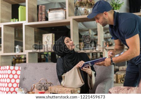 Courrier giving the goods to the girl wearing hijab in the coffe shop.