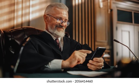 Court of Law and Justice on a Coffee Break: Smiling Male Judge Using Smartphone, Browsing Online Content, Using Social Media App, Investing, Internet e-commerce Purchases.