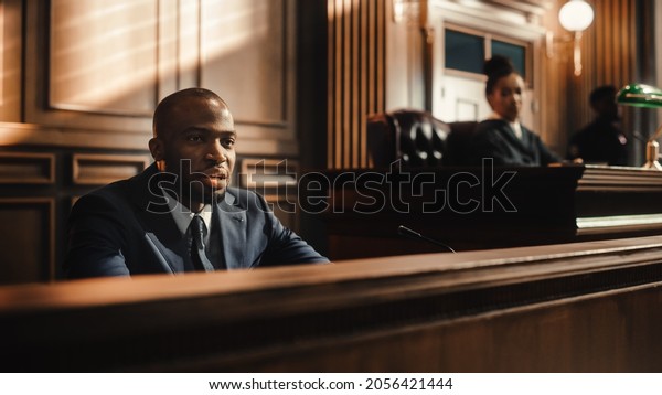 Court of Law and Justice Trial Stand: Portrait\
of Handsome Male Witness Giving Testimony to Judge, Jury. Speech of\
Hardened Criminal Denying Charges, Lying, Accusing Victims,\
Committing Perjury.
