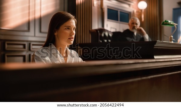 Court of Law and Justice Trial Stand: Portrait\
of Beautiful Female Victim Giving Heartfelt Testimony, Judge and\
Jury Listening. Dramatic Speech of Empowered Witness against Crime,\
Prejudice, Injustice