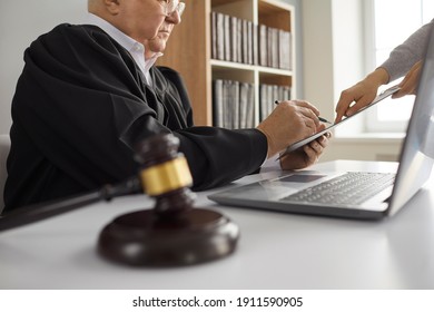 Court order being signed at courthouse. Senior judge sitting at table with laptop computer and gavel and signing divorce decree or other official proclamation given by lawyer. Law and justice concept - Shutterstock ID 1911590905
