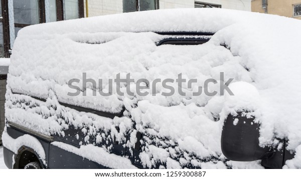 Courtyard\
after heavy snowfall. The car, covered with thick layer of snow.\
Right side of a luxury car covered with\
snow