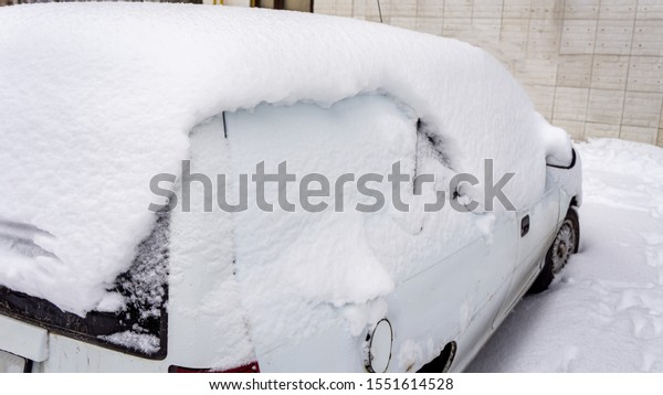 Courtyard\
after heavy snowfall. The car, covered with thick layer of snow.\
Right side of a luxury car covered with\
snow