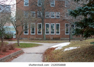 The Courtyard And Exterior Of A University Dormitory Building Made Of Red Brick With White Trim. The Multi-story Building Has Rows Of Windows On Each Floor. The Garden Has Trees, Grass And Sidewalks. 