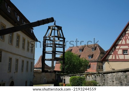 Courtyard of Medieval Crime Museum, wooden torture cage, device for torturing witches with water, historical buildings at old town, Rothenburg ob der Tauber, Bavaria, Germany