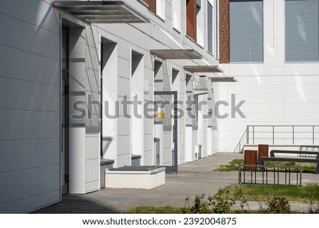 The courtyard of residential buildings with benches. View of the new residential complex. Arrangement of yard infrastructure. Sidewalk along the houses, with benches at the entrances.