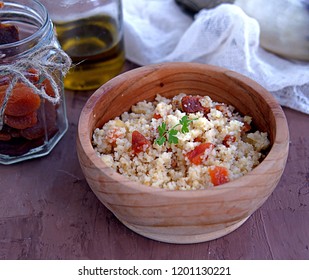 Couscous with dried apricots and fried onions in a wooden bowl. Traditional Moroccan dish. Healthy food.