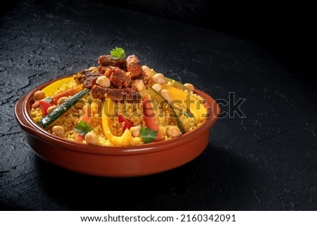 Couscous with meat and vegetables, festive Tunisian food with chickpeas, on a dark background with copy space