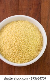 couscous in white bowl on brown background