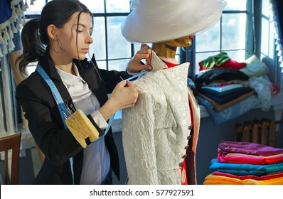 Couturier sews a dress in the studio