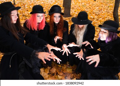 Coven Of Witches, Modern Witches Gathered And Do A Ritual In The Park. Halloween, A Group Of Different Women Like Witches In Black And Hats.