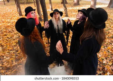 Coven Of Witches, Modern Witches Gathered And Do A Ritual In The Park. Halloween, A Group Of Different Women Like Witches In Black And Hats.