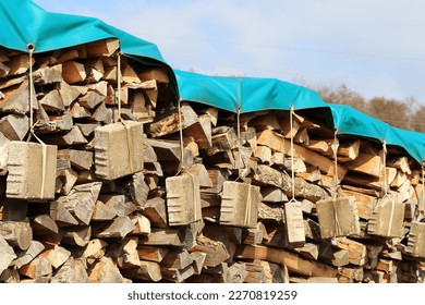 Cover tarps on wood pile, secure with hanging stones.