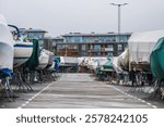 covered boats on metal stands in marina or boatyard on overcast day