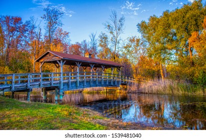 Covered bridge along a creek in Robert H. Long Nature Park in Commerce Township Michigan during sunset in the fall.
