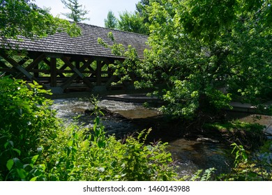 Covered Bridge With Trees Along The Naperville Riverwalk Over The DuPage River