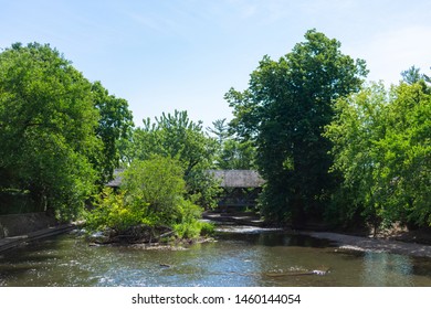 Covered Bridge With Trees Along The Naperville Riverwalk Over The DuPage River