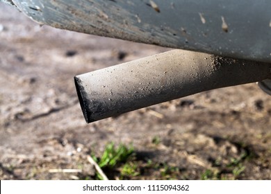 covered with dirt and black carbon car exhaust pipe, on the road from sand