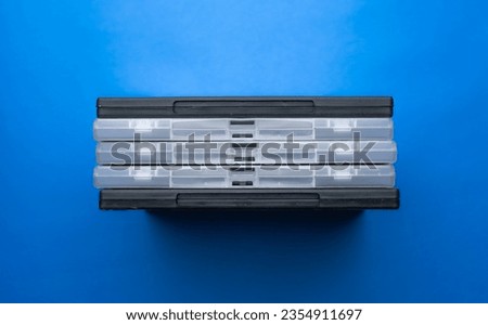 Covered DVD cases are lined up side by side. Transparent and black movie DVD boxes. Blue Background, top angle.