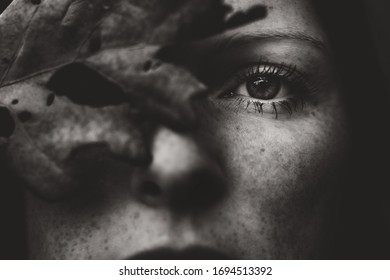covered eye of young woman with leaf in autumn