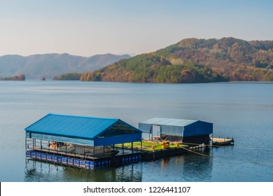 Covered Floating Boat Dock In Calm Lake On Autumn Day With Trees In Fall Colors In Background.