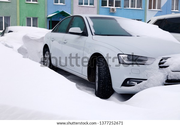 Сar\
covered with snow stands in the parking lot of residential building\
in winter. Сoncept of bad weather, snowfall, harsh weather\
conditions, frost, blizzard, car engine did not\
start