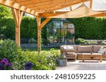 covered terrace with furniture in the garden, glasshouse in the background