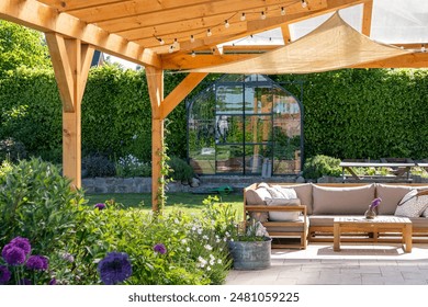 covered terrace with furniture in the garden, glasshouse in the background - Powered by Shutterstock