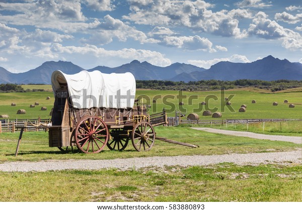 covered wagon against\
a mountain landscape