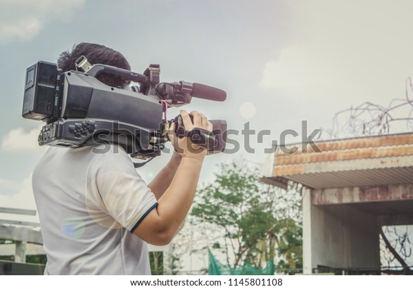 Covering an\
event with a video camera., Videographer takes video camera., Video\
cameran operate working at the\
street.