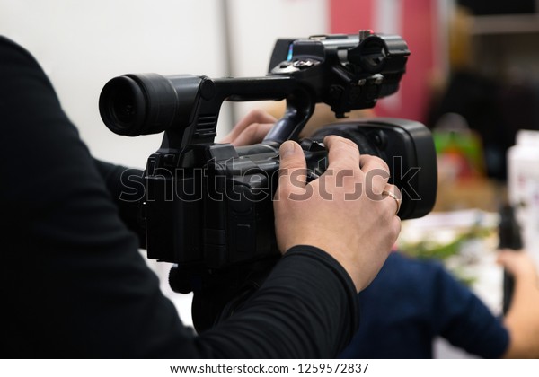 Covering an event with a\
video camera. Videographer films with video camera. Camera operator\
working indoors