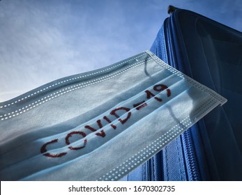 COVID 19 Coronavirus On Medical Protective Mask. Blue Suitcase Concept For Travelling In Corona Virus Outbreak Season. Travel Ban Block Forbidden. Pandemy Of Korona Virus Spreading All Over The World