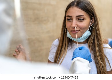 Covid 19 lifestyle concept of a young woman with lowered face mask performs a nasal swab for coronavirus.
