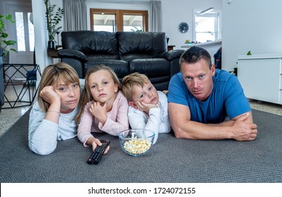 COVID 19 Outbreak. Bored And Frustrated Family Watching Tv At Home Feeling Depressed  Mental Health Impact Of Lockdown Social Distancing And Job Losses Due To Coronavirus.