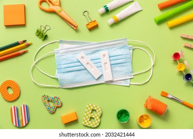 Covid 19 Rapid Self Test, Protective Medical Mask And School Supplies On Pastel Green Background, Top View. Back To School 2021, Coronavirus Spread Prevention Measures For Students Flat Lay.