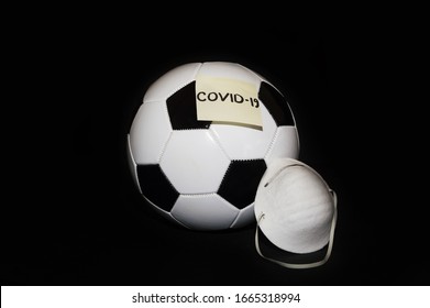 Covid 19 Stops Soccer, Football And Other Sports. Soccer Ball With Surgery Mask And Post-it. Coronavirus Effects And Consequences On Sports. 