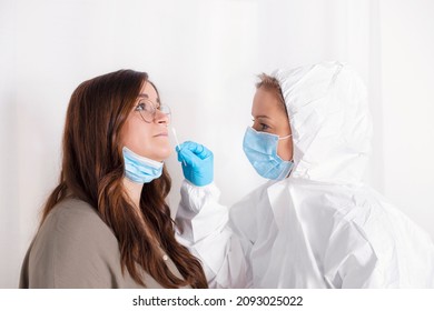 Covid 19 Test. Laboratory Worker Wearing Personal Protective Equipment Testing Young Woman For Coronavirus Using Nasal Swab Method.