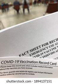 Covid 19 Vaccination Card And Fact Sheet In Waiting Are With Socially Distant People In Background
