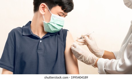 COVID 19 Vaccines For Kids And Teenager Issue. A Smart Asian Teen Boy With Medical Face Mask About To Get A Vaccine Shot At The Hospital. Safe, Authorized, Back To School, Insurance, Healthcare.