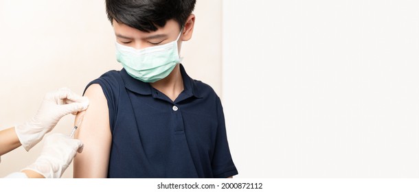 COVID 19 Vaccines For Kids And Teenager Issue. Smart Asian Teen Boy With Medical Face Mask About To Get A Vaccine Shot At The Hospital. Safe, Authorized, Back To School, Insurance, Healthcare.