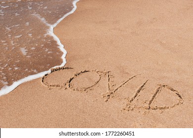 Covid free, stop Covid, safe beach and holiday, word written on the sand with wave washing and cleaning, vaccine
