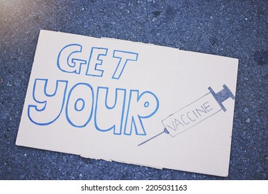 Covid, Vaccine And Poster With A Sign On The Ground Outside During The Corona Virus Pandemic. Propaganda, Motivation And Advertising With Writing On A Board For Vaccination, Healthcare And Medicine