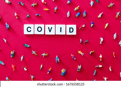 COVID word on a red background with miniatures of people. Social distancing concept to avoid coronavirus covid-19 outbreak. Distance between people to avoid spread of pandemic disease. Copyspace