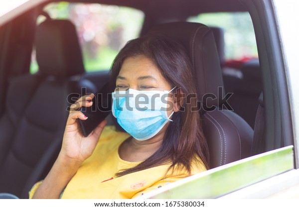 Covid-19 and Air pollution pm2.5 concept.Indian\
illness woman taking phone panic and fear and coughing in truck car\
wearing protection mask from virus.Covid-19 coronavirus and\
pandemic virus\
symptoms.