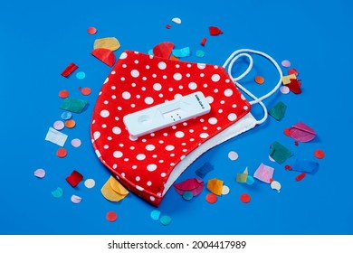 A Covid-19 Antigen Diagnostic Test Device, A Red Face Mask Patterned With White Dots And Some Confetti On A Blue Background, As A Safe Party Set