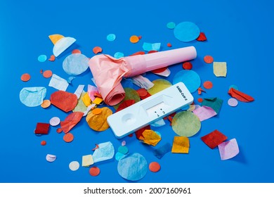 A Covid-19 Antigen Diagnostic Test Device, A Pink Party Horn And Some Multicolored Confetti On A Blue Background, As A Safe Party Set