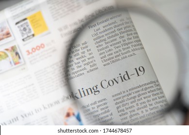 COVID-19 Article On A Newspaper Through A Magnifying Glass. COVID-19 PANDEMIC. HEADLINES. NEWSPAPER.