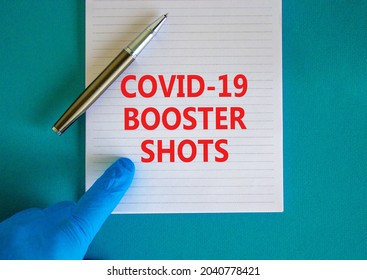 Covid-19 booster shots vaccine symbol. White note with words Covid-19 booster shots, beautiful blue background, doctor hand and metallic pen. Covid-19 booster shots vaccine concept.